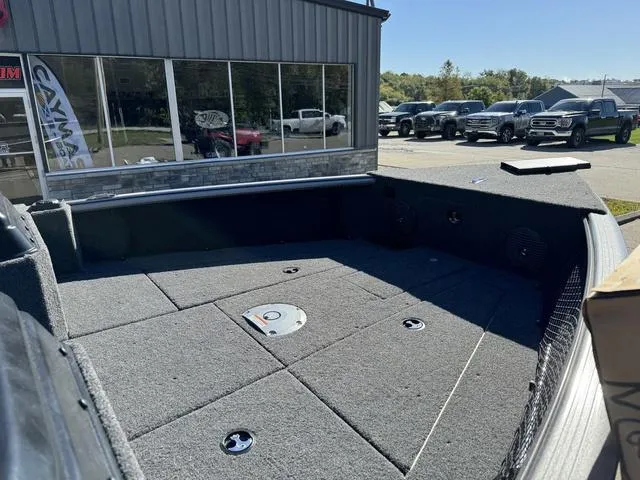 Slide: The Image of 2025 Lund 1875 Impact XS Sport boat interior with carpeted deck in a dealership lot. - 16
