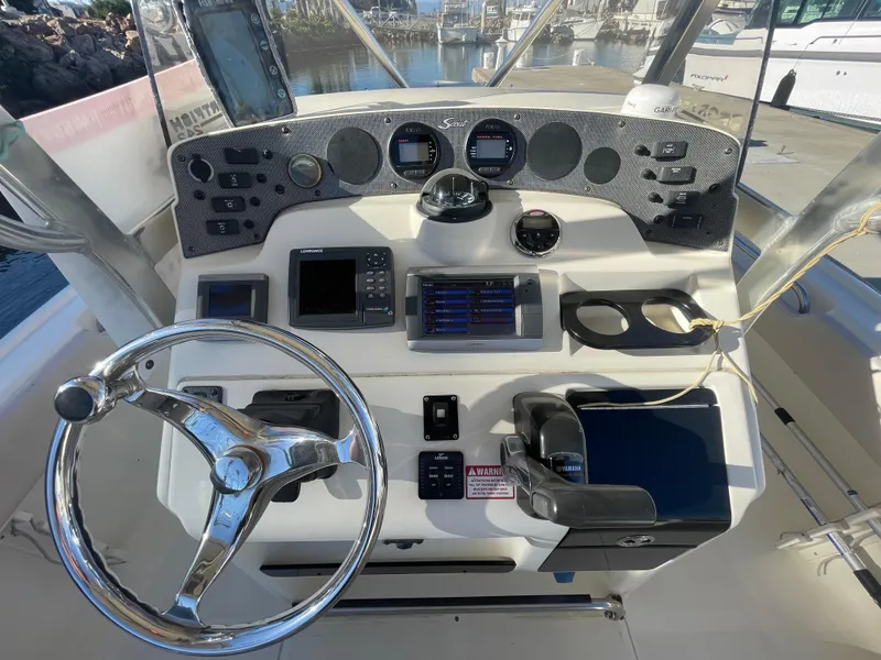 Slide: The Image of 2007 Scout 242 Sportfish boat dashboard with steering wheel and navigation instruments. - 16