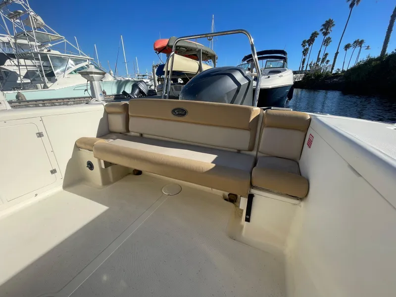 Slide: The Image of 2007 Scout 242 Sportfish boat interior with seating, docked under clear blue sky. - 4