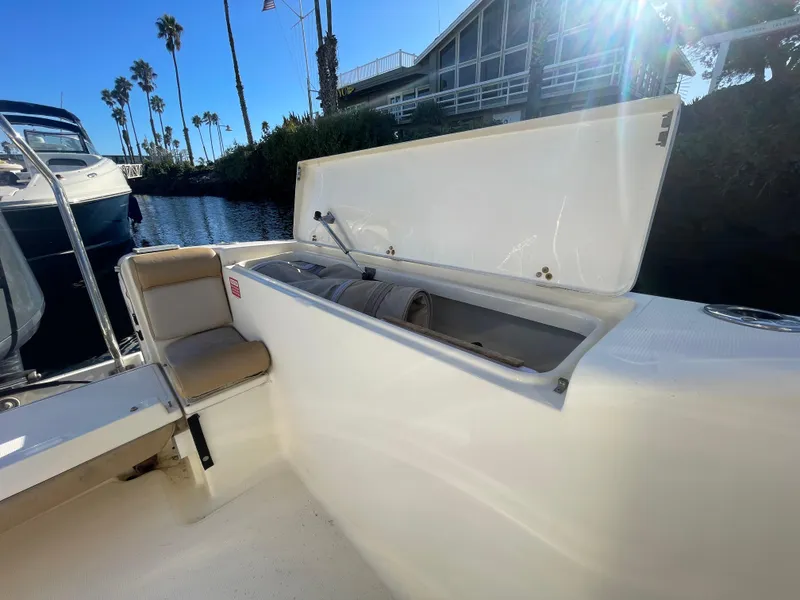 Slide: The Image of 2007 Scout 242 Sportfish boat with open storage compartment, docked near palm trees. - 6
