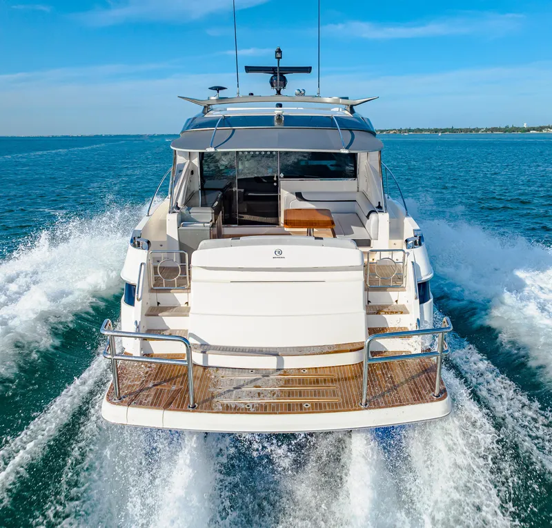Slide: The Image of 2025 Riviera 5400 Sport Yacht cruising on open water, rear view. - 14