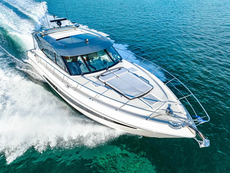 Slide: The Image of 2025 Riviera 5400 Sport Yacht cruising on clear blue water. - 19