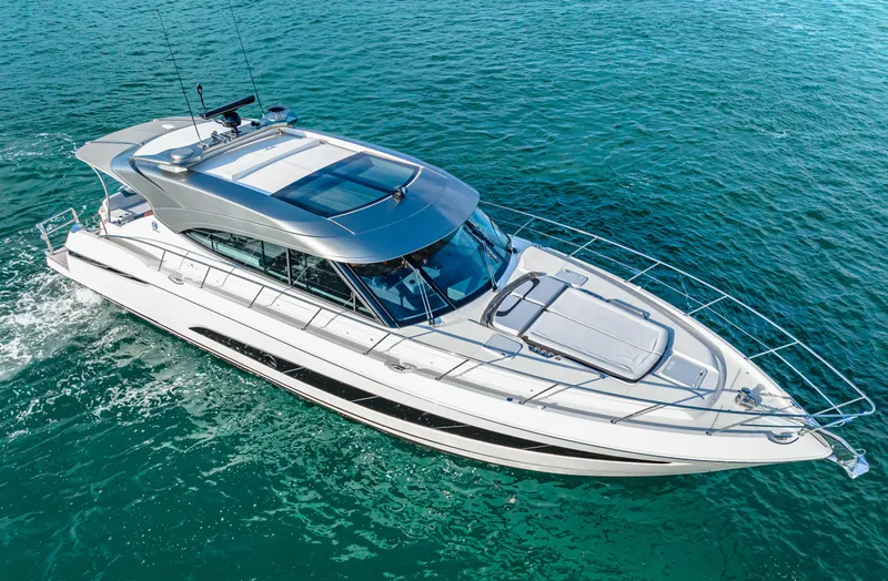 Slide: The Image of 2025 Riviera 5400 Sport Yacht cruising on clear blue water. - 2