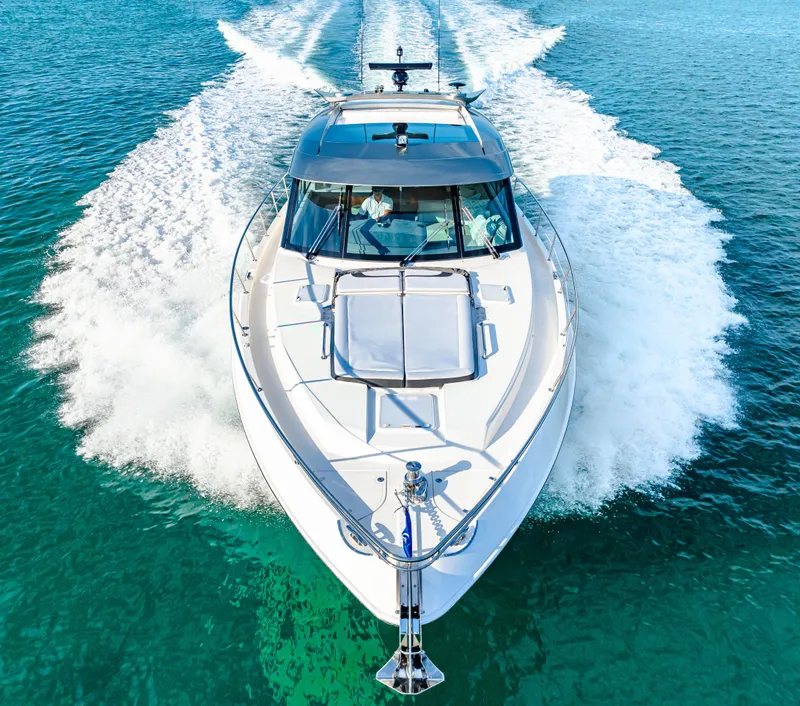 Slide: The Image of 2025 Riviera 5400 Sport Yacht cruising on clear blue water. - 20