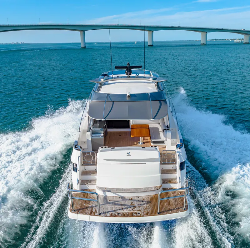 Slide: The Image of 2025 Riviera 5400 Sport Yacht cruising under a bridge on open water. - 21