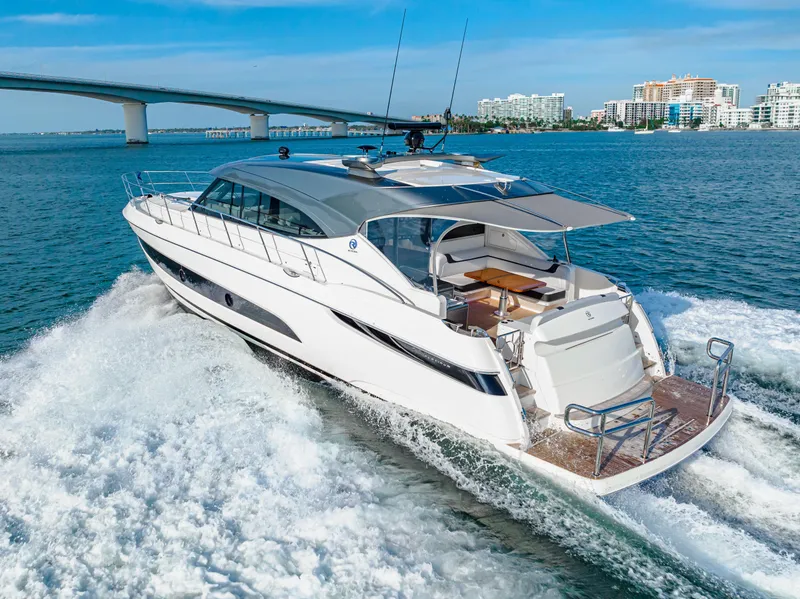 Slide: The Image of 2025 Riviera 5400 Sport Yacht cruising on open water near a bridge. - 22