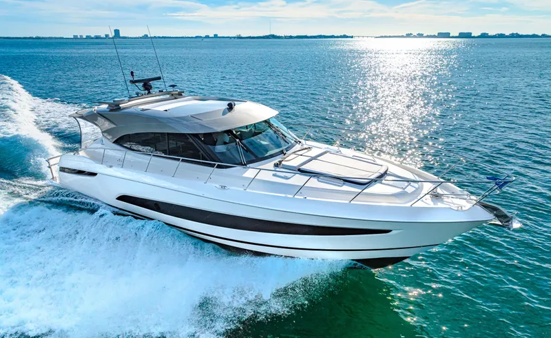 Slide: The Image of 2025 Riviera 5400 Sport Yacht cruising on open water under clear skies. - 24