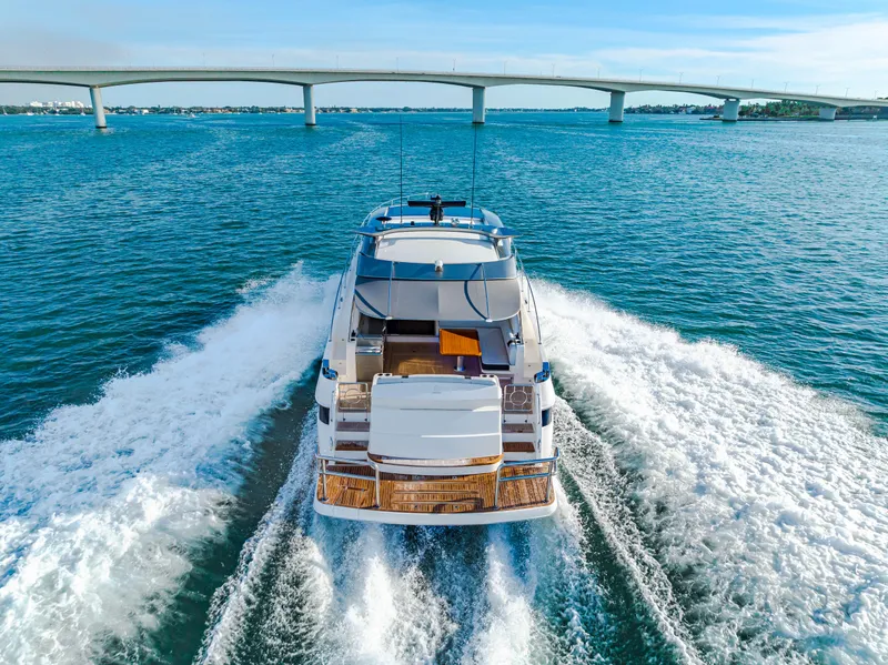 Slide: The Image of 2025 Riviera 5400 Sport Yacht cruising under a bridge on open water. - 25