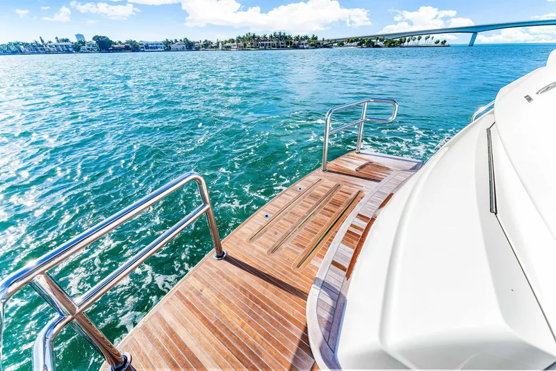 Slide: The Image of 2025 Riviera 5400 Sport Yacht on serene blue waters, featuring elegant wooden deck. - 36