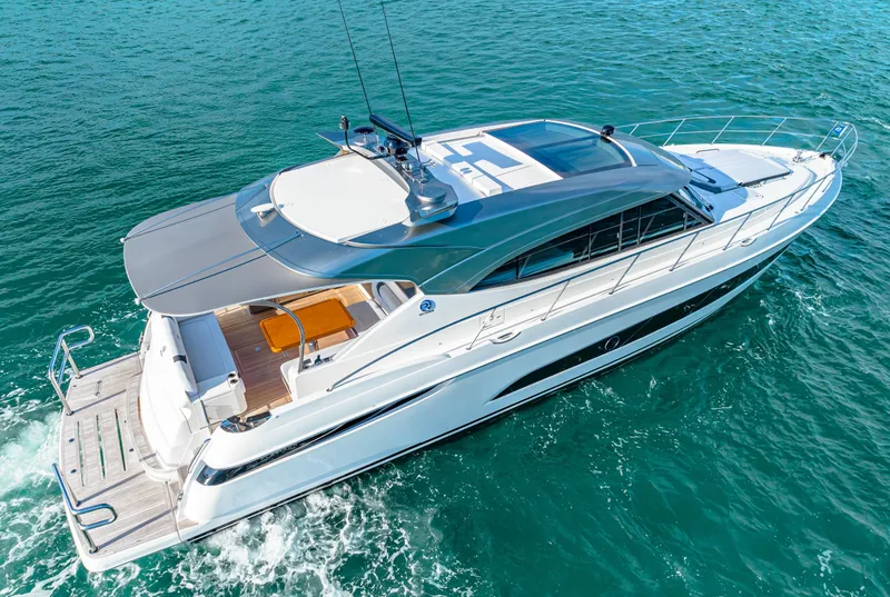 Slide: The Image of 2025 Riviera 5400 Sport Yacht cruising on clear blue water. - 4