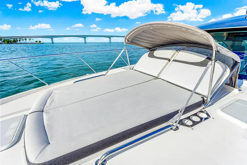 Slide: The Image of 2025 Riviera 5400 Sport Yacht with sunbed, ocean view, and bridge in background. - 43