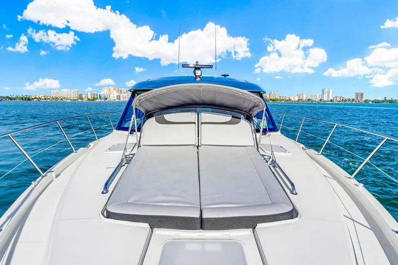 Slide: The Image of 2025 Riviera 5400 Sport Yacht on open water, sunny day, city skyline in background. - 45