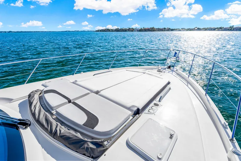 Slide: The Image of 2025 Riviera 5400 Sport Yacht cruising on a sunny day, featuring spacious deck and ocean view. - 46