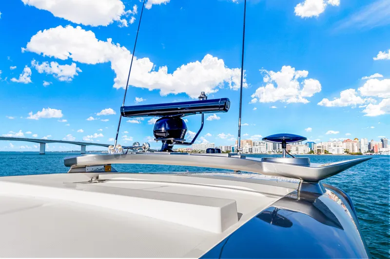 Slide: The Image of 2025 Riviera 5400 Sport Yacht on water, clear sky, cityscape in background. - 48