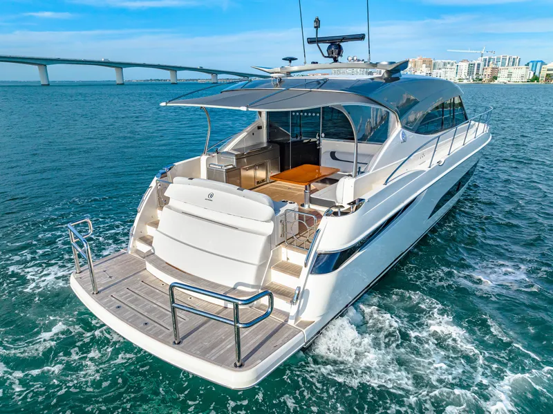 Slide: The Image of 2025 Riviera 5400 Sport Yacht cruising on open water near a bridge. - 5