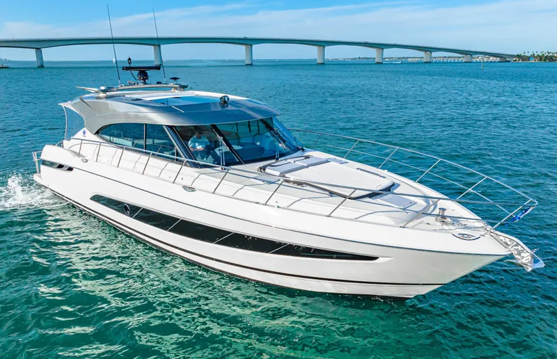 Slide: The Image of 2025 Riviera 5400 Sport Yacht cruising on blue water near a bridge. - 9