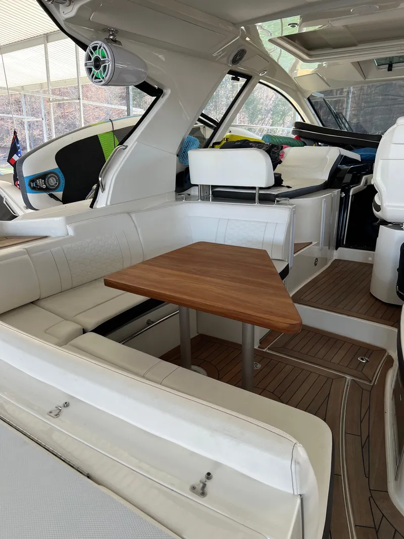Slide: The Image of Interior of 2018 Sea Ray Sundancer 350 Coupe with white seating and wooden table. - 11
