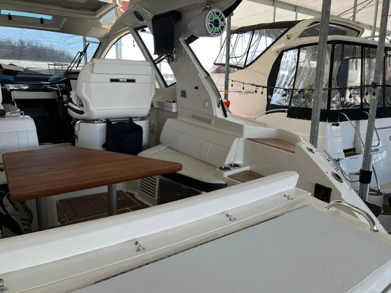 Slide: The Image of 2018 Sea Ray Sundancer 350 Coupe interior with seating and wooden table. - 8