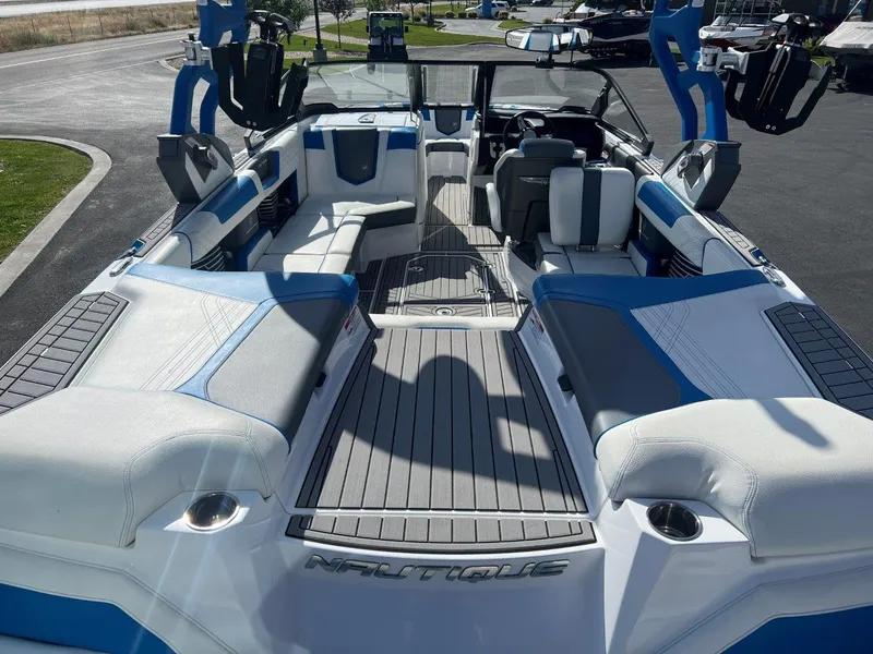 Slide: The Image of 2020 Nautique G23 boat interior with blue and white seating, docked outdoors. - 11