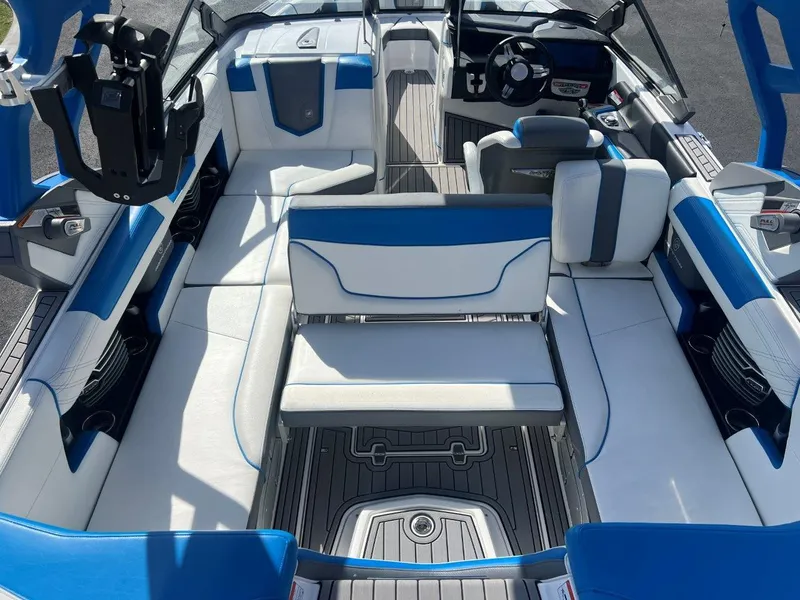 Slide: The Image of 2020 Nautique G23 boat interior with blue and white seating, steering wheel, and deck. - 12