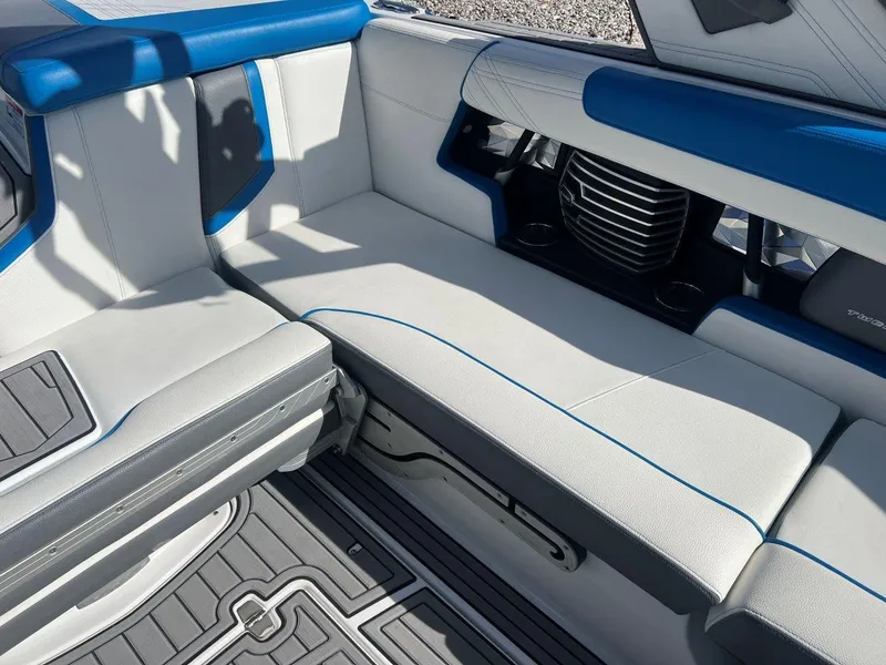 Slide: The Image of 2020 Nautique G23 boat interior with white and blue seating, cup holders, and sleek design. - 14