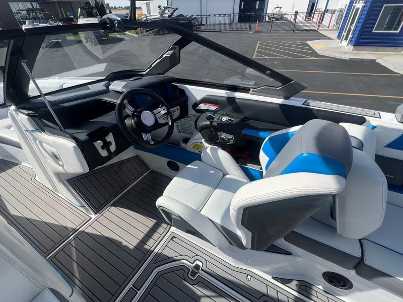 Slide: The Image of 2020 Nautique G23 boat interior with modern steering and blue-accented seating. - 16