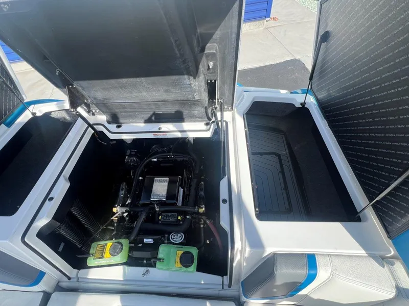 Slide: The Image of 2020 Nautique G23 engine compartment with open hatches, showcasing the engine and storage areas. - 20