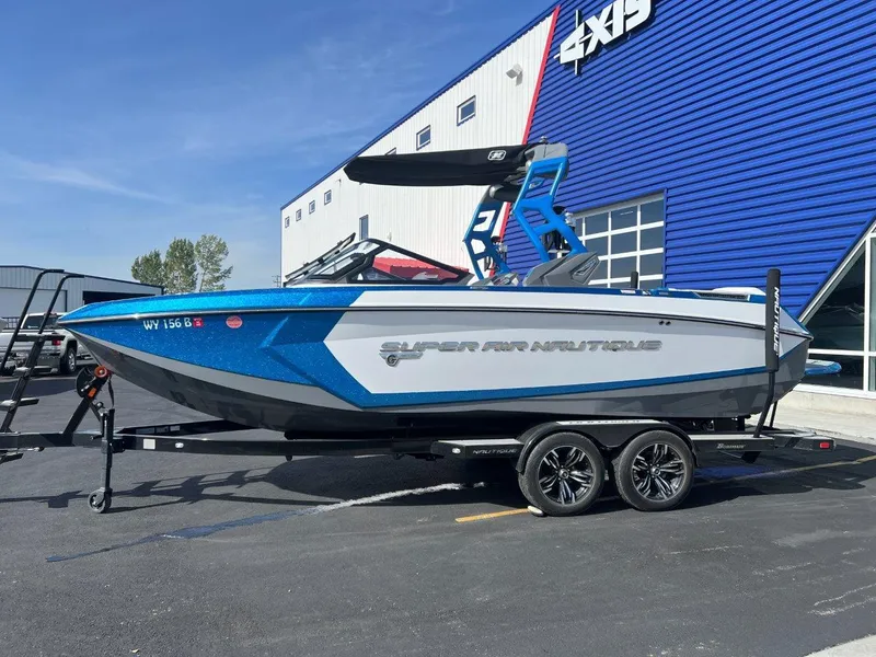 Slide: The Image of 2020 Nautique G23 boat on trailer, blue and white, parked outside a building. - 4