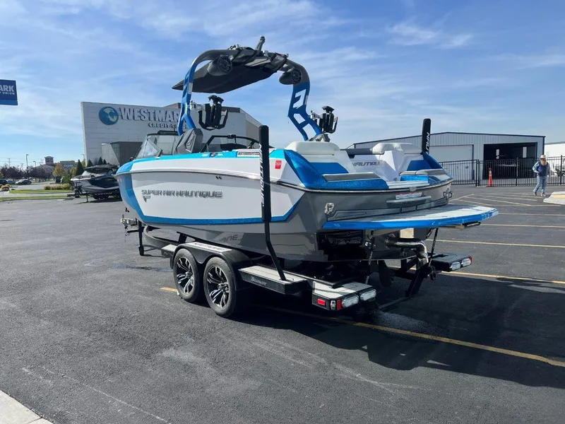 Slide: The Image of 2020 Nautique G23 boat on trailer in parking lot, blue and white design. - 5
