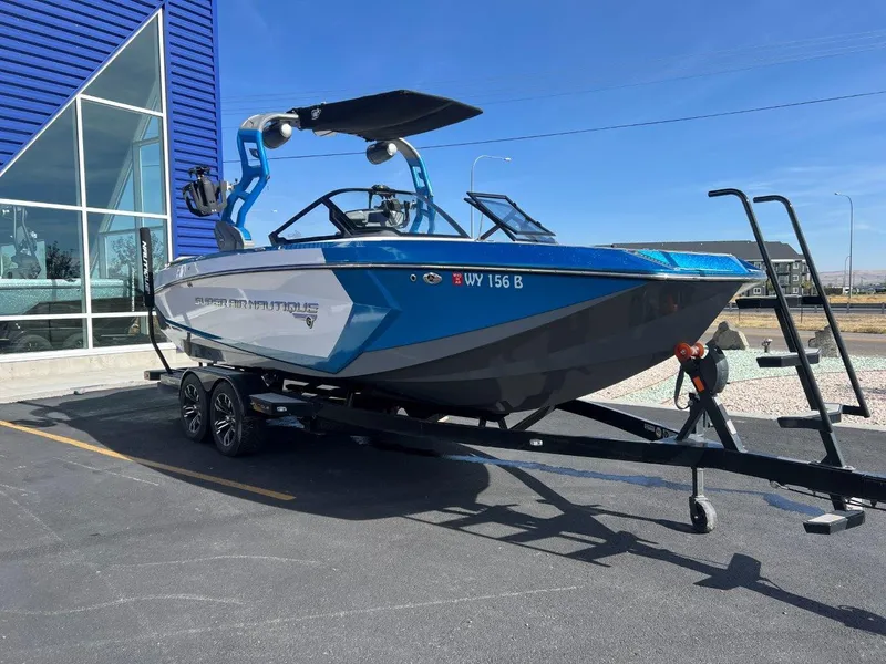 Slide: The Image of 2020 Nautique G23 boat on trailer, parked near a modern building. - 9