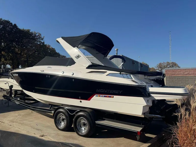 Slide: The Image of 2015 Monterey 288SS boat on trailer, parked outdoors under clear blue sky. - 2