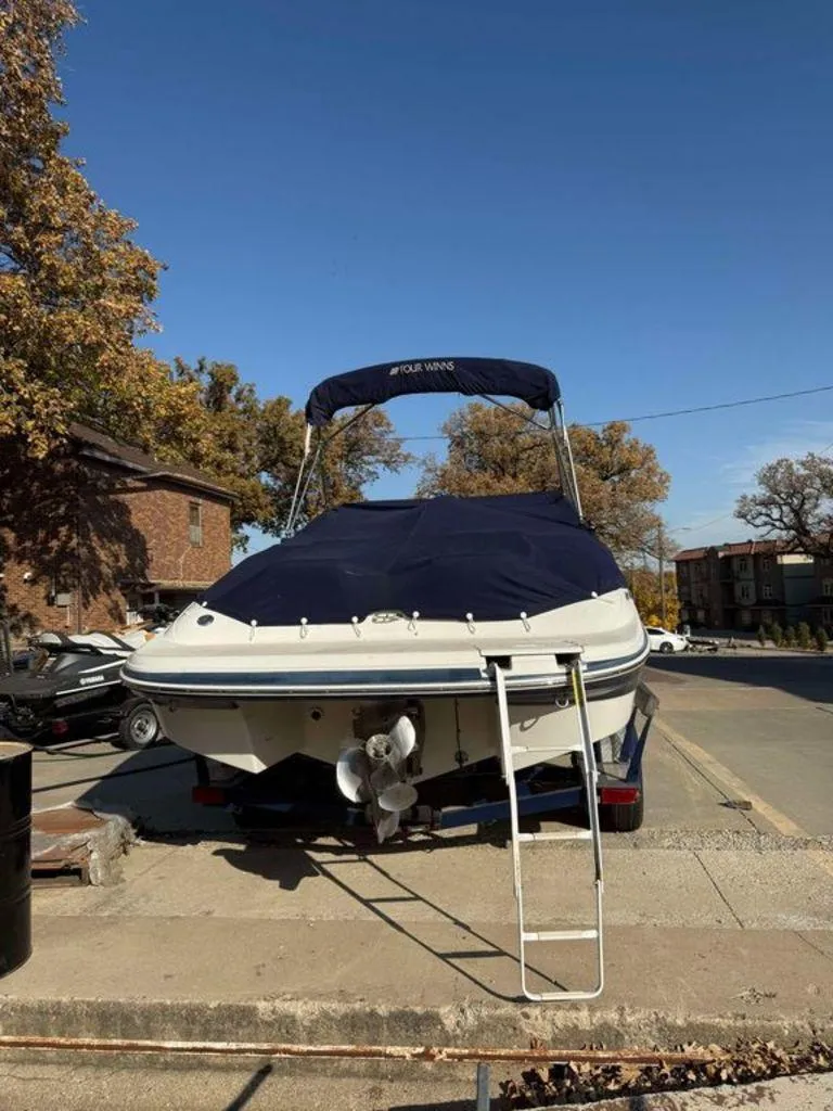 Slide: The Image of 2004 Four Winns 230 Horizon boat with cover and ladder, parked outdoors. - 10