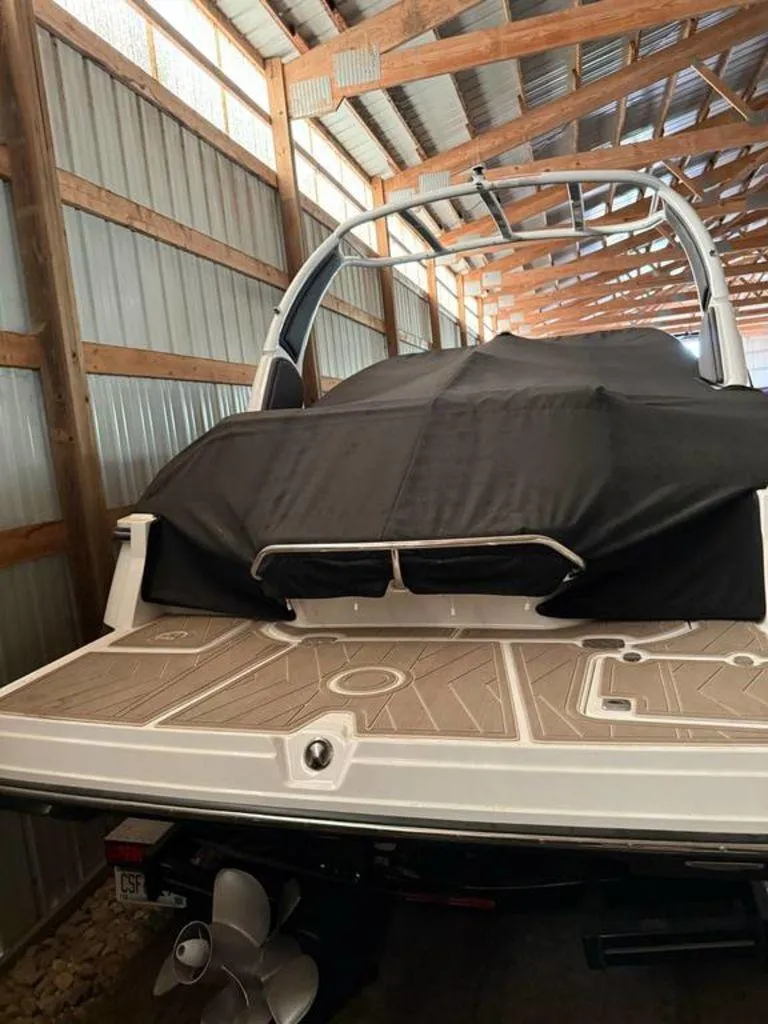 Slide: The Image of 2016 Sea Ray SLX 250 boat stored in a wooden shed, covered with a black tarp. - 1