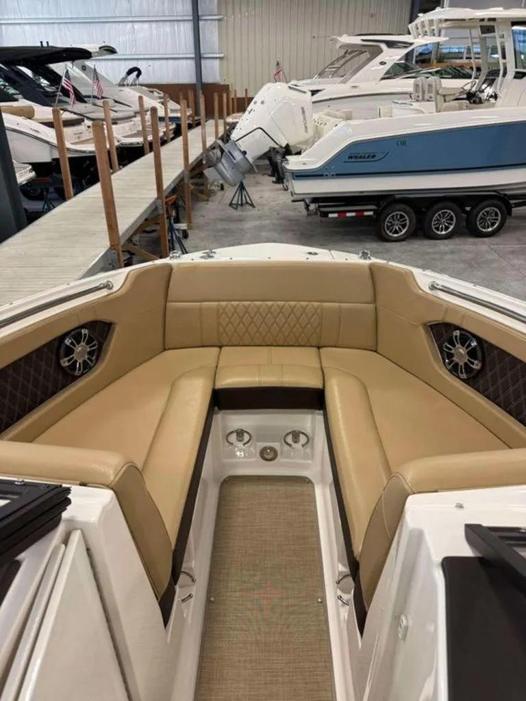 Slide: The Image of 2019 Sea Ray SLX 230 boat interior with tan seating in a showroom. - 2