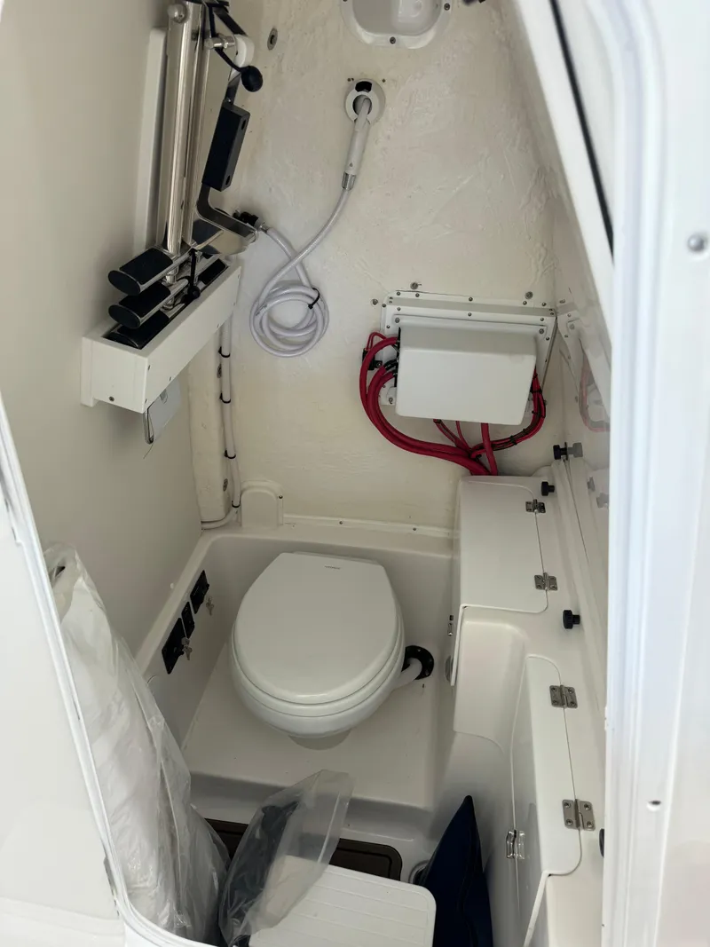 Slide: The Image of 2024 Tidewater 272 CC Adventure boat interior with compact marine toilet and storage. - 13