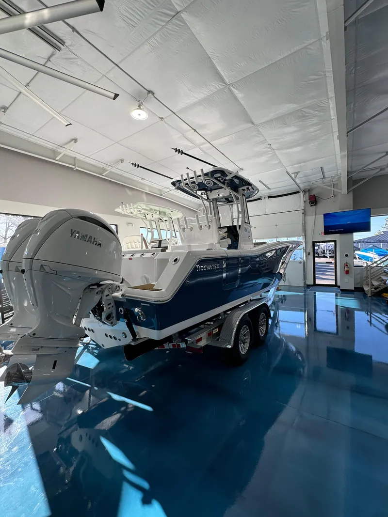 Slide: The Image of 2024 Tidewater 272 CC Adventure boat in showroom, featuring dual outboard engines. - 2