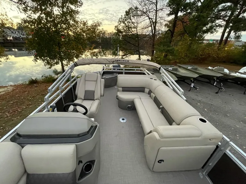 Slide: The Image of 2025 Sun Tracker SportFish 20 DLX pontoon boat with spacious seating by a serene lake. - 2