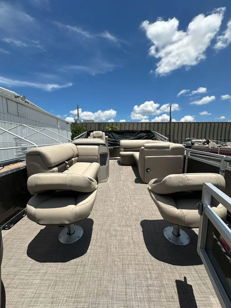 Slide: The Image of 2025 Sun Tracker Fishin' Barge 20 DLX with beige seating under a clear blue sky. - 10