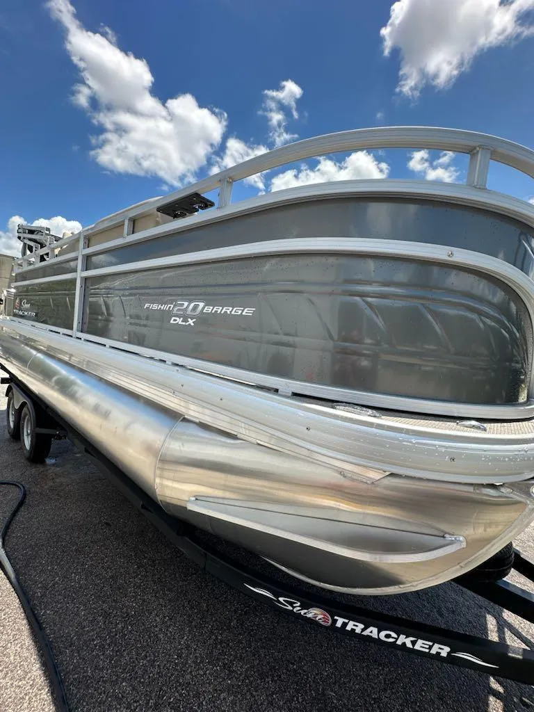 Slide: The Image of 2025 Sun Tracker Fishin' Barge 20 DLX pontoon boat under a blue sky. - 11