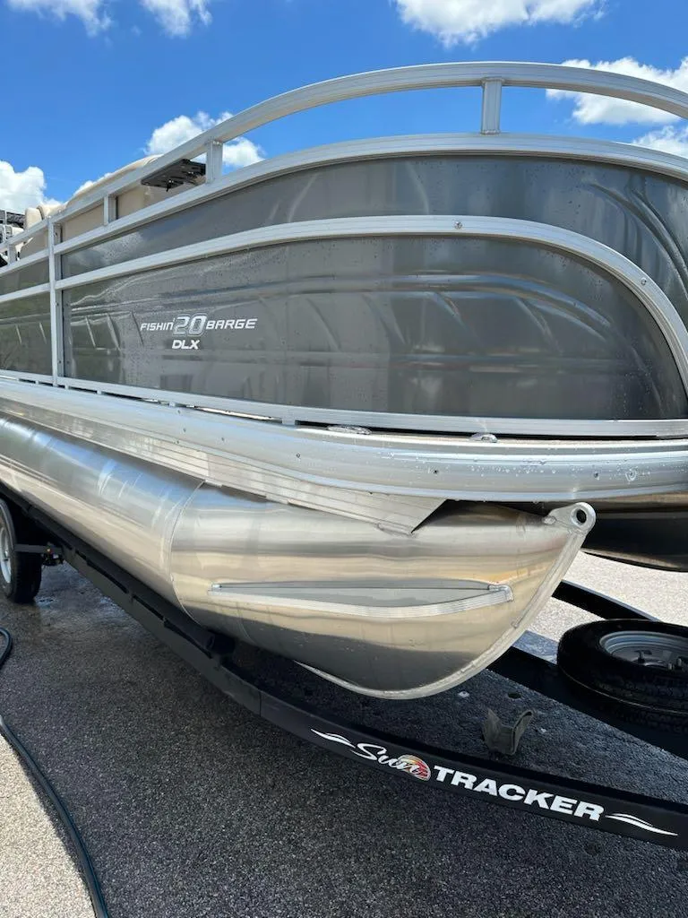 Slide: The Image of 2025 Sun Tracker Fishin' Barge 20 DLX pontoon boat on trailer under blue sky. - 3