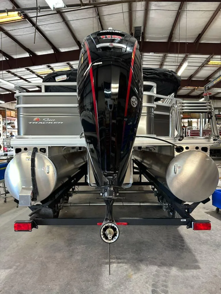 Slide: The Image of 2025 Sun Tracker Fishin' Barge 20 DLX pontoon boat with powerful outboard motor in a warehouse. - 8