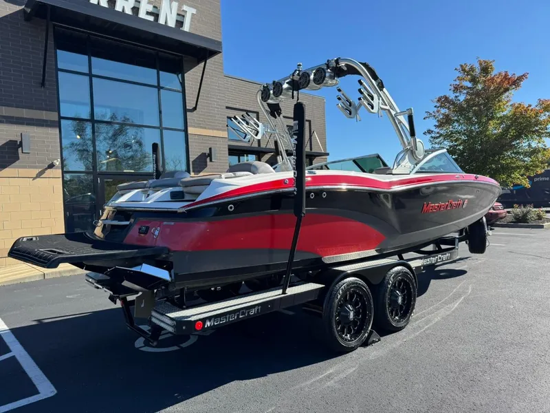 Slide: The Image of 2014 MasterCraft X46 boat on trailer, red and black, parked outside a building. - 4