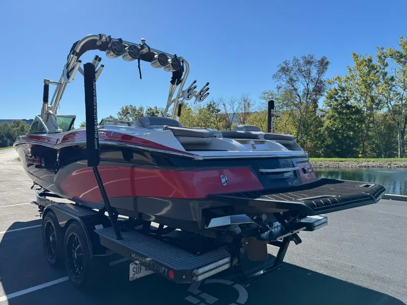 Slide: The Image of 2014 MasterCraft X46 boat on trailer, parked near a lake with trees in the background. - 6