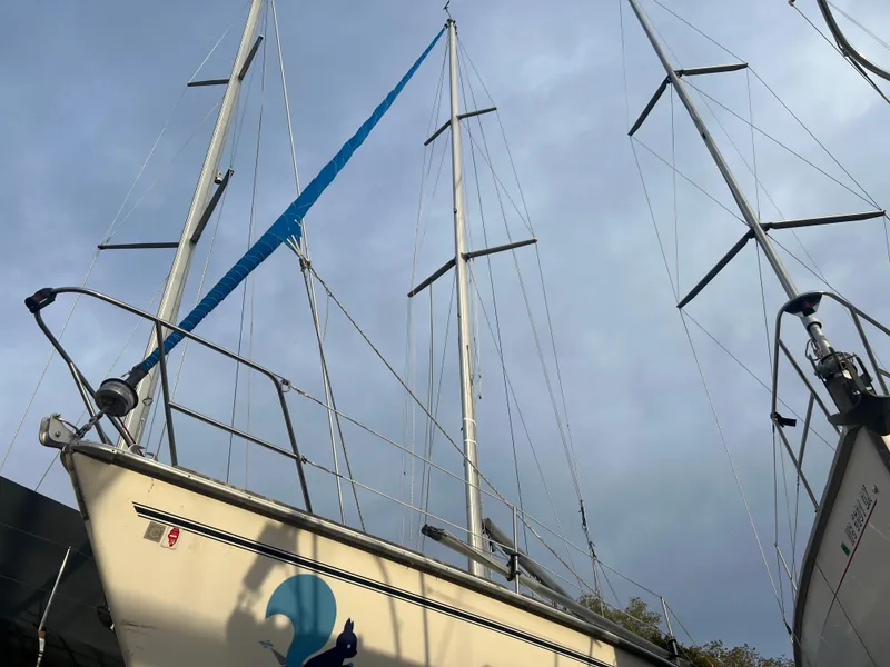 Slide: The Image of 1987 Pearson 31-2 sailboat with blue sail, docked under cloudy sky. - 21