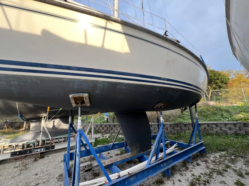 Slide: The Image of 1987 Pearson 31-2 sailboat on blue stands, displayed outdoors. - 22