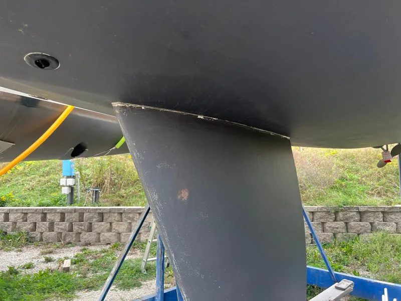 Slide: The Image of 1987 Pearson 31-2 sailboat keel and hull detail, on a stand outdoors. - 23