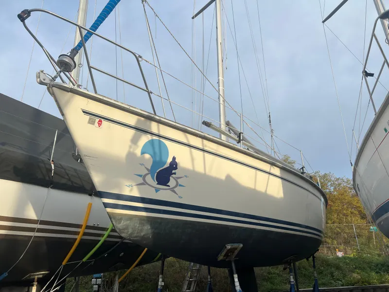 Slide: The Image of 1987 Pearson 31-2 sailboat with blue squirrel logo, docked on land. - 32