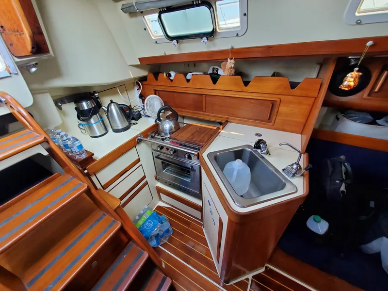 Slide: The Image of 1987 Pearson 31-2 yacht interior kitchen with wooden cabinetry, stove, and sink. - 7