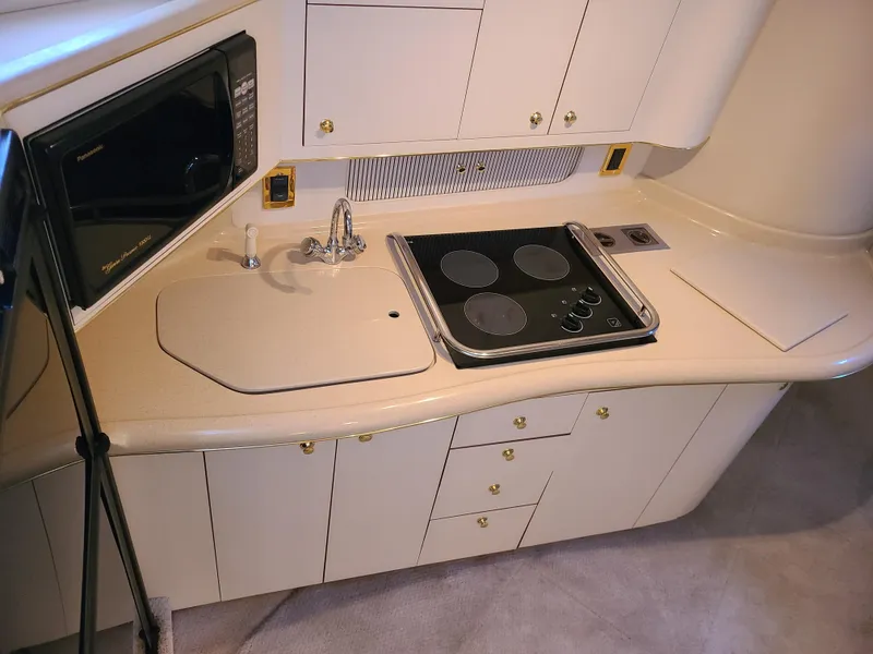 Slide: The Image of 1998 Sea Ray 400 Sundancer yacht kitchen with stove, sink, and microwave. - 13