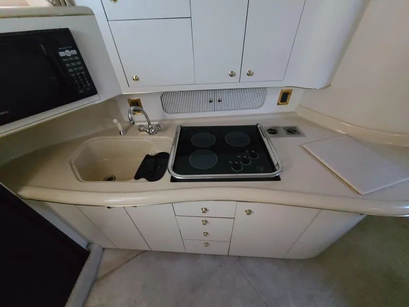 Slide: The Image of 1998 Sea Ray 400 Sundancer kitchen with stove, sink, and cabinets. - 25